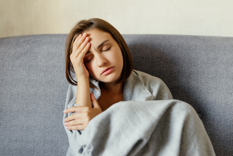 stressed woman with broken furnace with blanket on couch