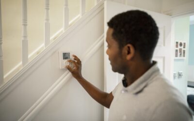 man pressing buttons on thermostat